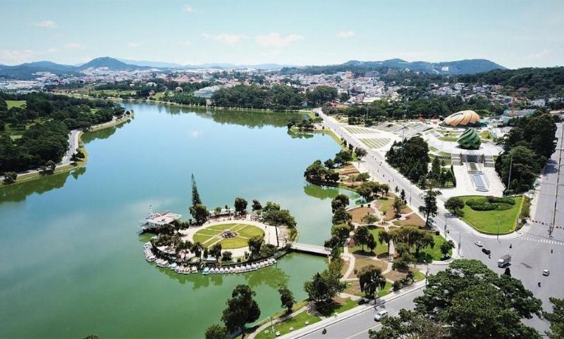 Du khách đội ô đi dạo bên hồ Xuân Hương vào buổi chiều tháng 6